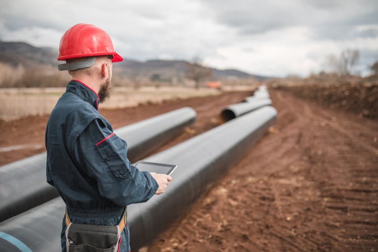 A worker in uniform checks gas pipes