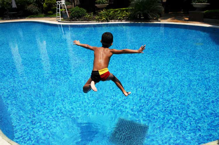 The asian boy jumps into blue water