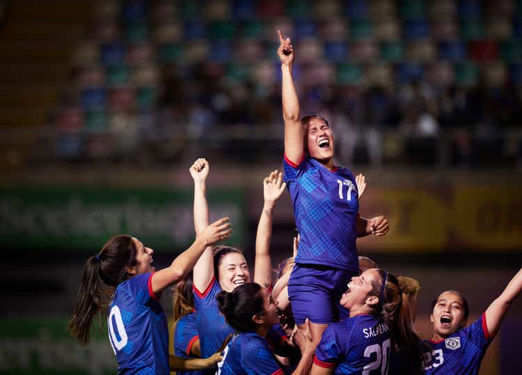 Celebrating women soccer players raise up their star player after winning the final in an international cup