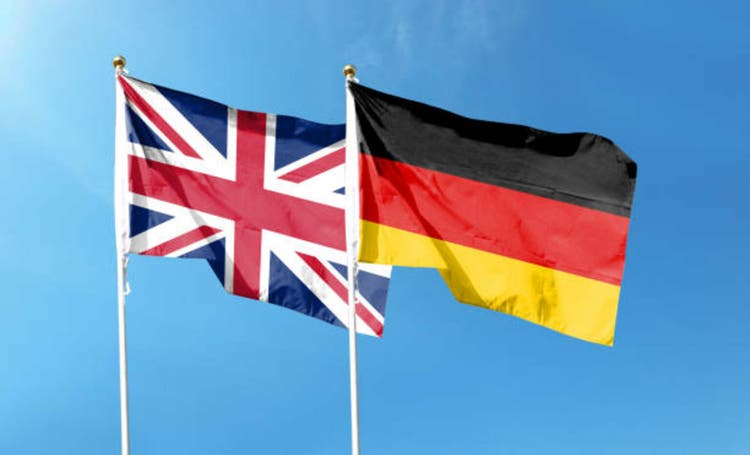 Union Jack and German flag on cloudy sky. waving in the sky