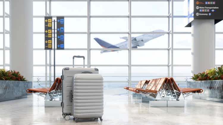 Área de espera del aeropuerto con equipaje, asientos vacíos y fondo borroso