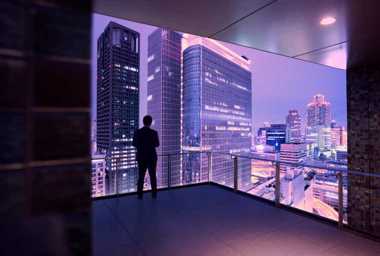 Businessman looking at futuristic skyline of Osaka, Japan at dusk