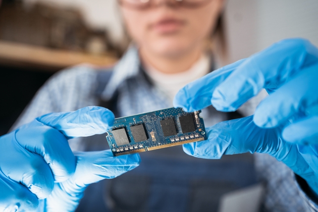Service technician with memory on a computer motherboard. RAM in hand on the background of the repair shop. Upgrading the personal computer