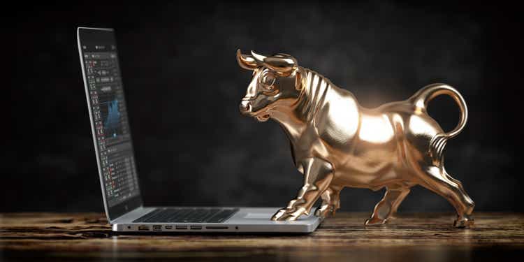 Bull market. Golden bull in front of laptop with stock charts. Financial investment and trading concept.