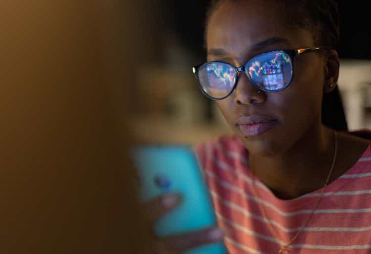 Woman checking stock market data with smart phone at home