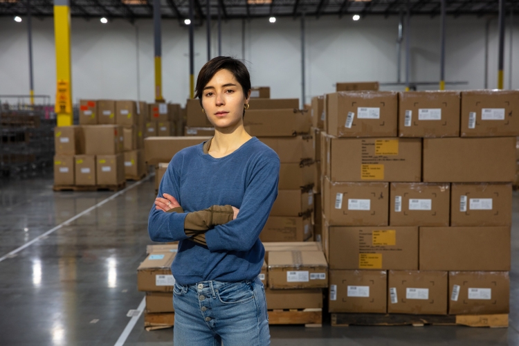 Young Hispanic Woman Looking At The Camera With Her Arms Crossed In a Fulfillment Center