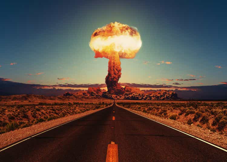 Asphalt road goes to a nuclear explosion. Terrible atomic explosion of a nuclear bomb with a mushroom cloud of radioactive dust. Hydrogen bomb test. Nuclear catastrophe. Way to nuclear war