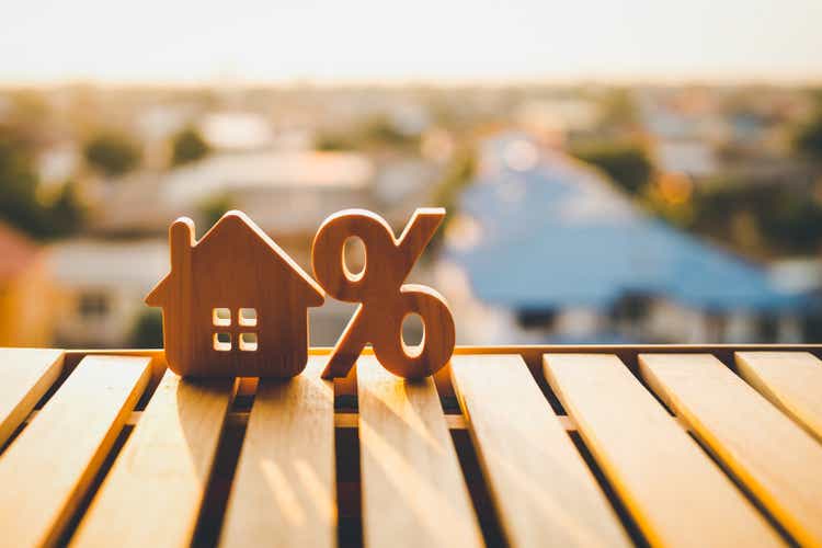 Percentage and house sign symbol icon wooden on wood table. Concepts of home interest, real estate, investing in inflation.