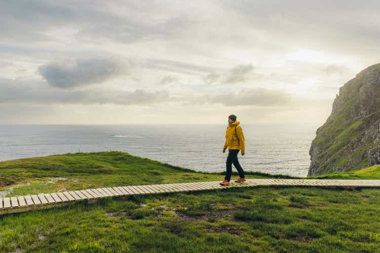 Man backpacker hiking on footpath on scenic Runde island with ocean view in Norway