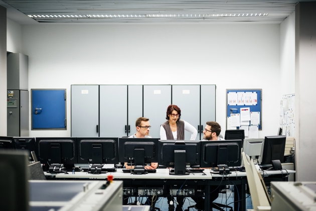 Mature female programmer guiding two engineers