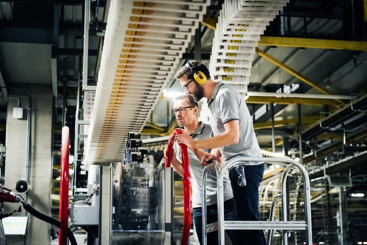 Two Engineers Examining Conveyor In A Printery