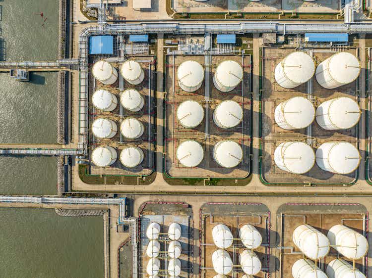 Many neatly arranged large cylindrical storage tanks by the seaside