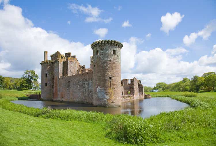 Castle surrounded by moat and green grass field