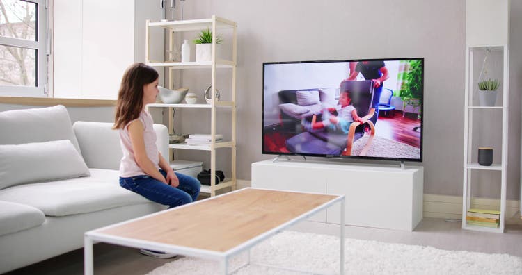Kid With Remote Control Sitting On Couch Watching Movie