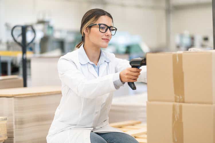 Female worker holding an RFID scanner and scanning the barcode of parcels in the delivery warehouse