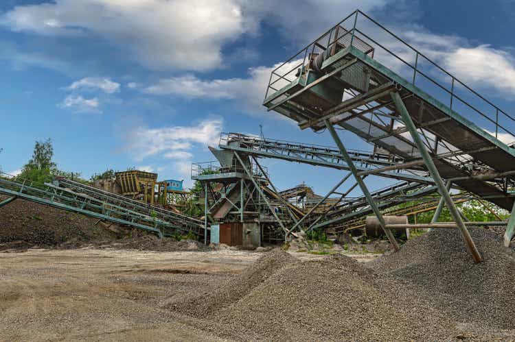 Crushing machinery, cone type rock crusher, conveying crushed granite gravel stone in a quarry open pit mining. Minning industry gravel quarry conveyor.