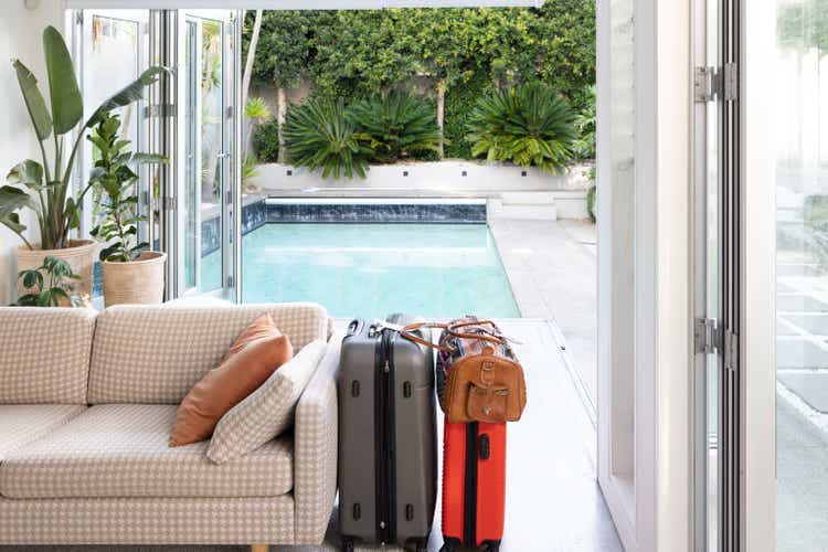 Sofa and packed suitcases inside in front of swimming pool