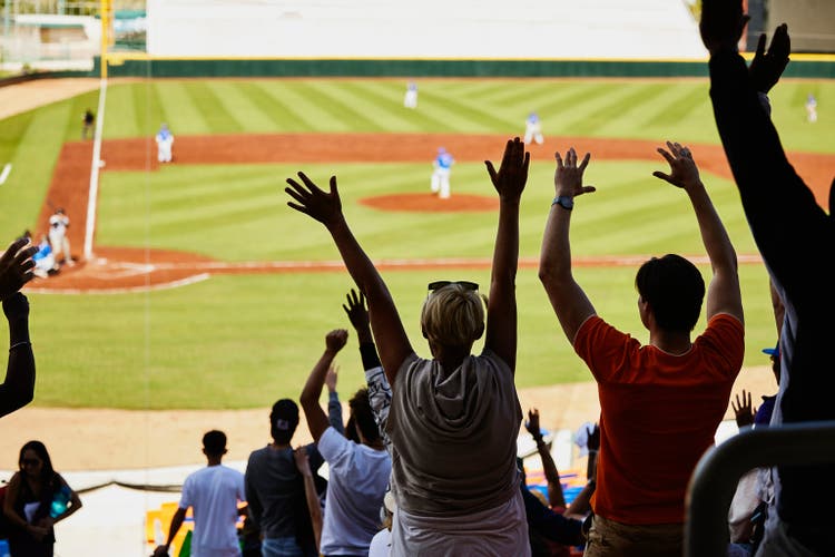 Wide shot stadium crowd standing and cheering baseball team during game