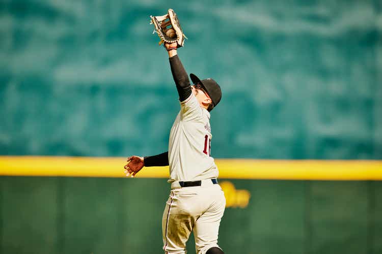 Medium wide shot of outfielder reaching for catch during baseball game