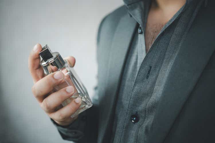 Handsome man in suit using perfume.