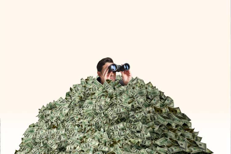 Man Buried In Pile of Cash Looks Through Pair Of Binoculars