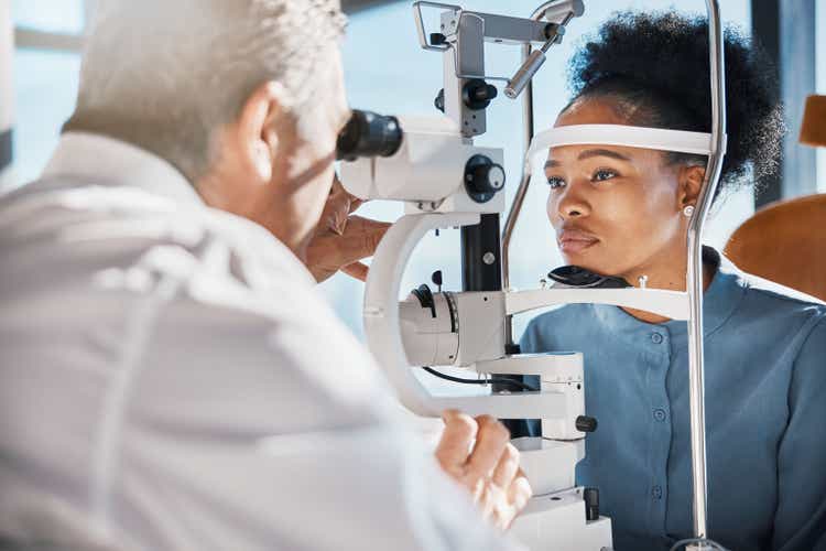 Help, eye exam or black woman consulting doctor for eyesight at optometrist or ophthalmologist. African customer testing vision with mature optician checking iris, glaucoma or retina visual health