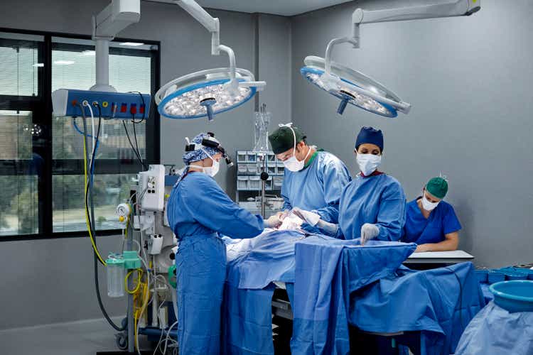 Surgeons and doctors in illuminated operating room