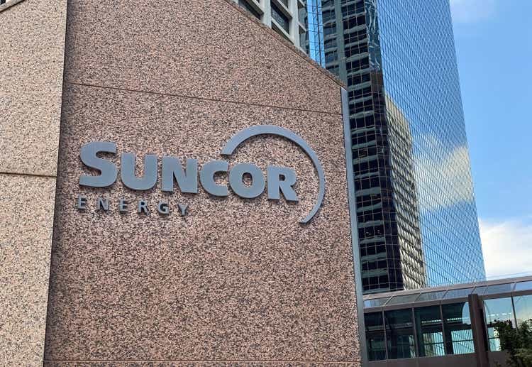 A close up to a Suncor sign with some building on the background.