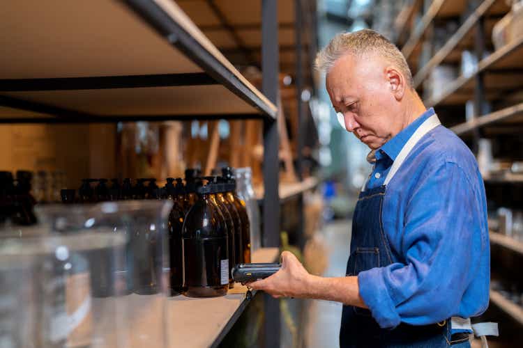 Good inventory management system keeps inventory organized and allows small businesses growth sustainable. Warehouse manager looking at digital tablet and walking in the storeroom inspector the product on shelf at home decoration factory.