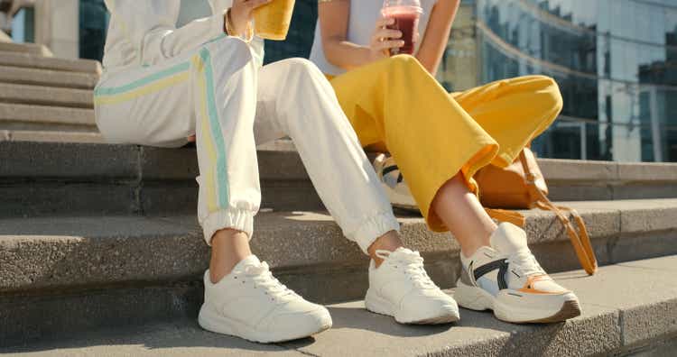 Friends, legs and shoes on city steps for bonding, travel and urban break with drinks, smoothie and beverage, Couple, people and town stairs for fashion, cool and trendy street style clothing