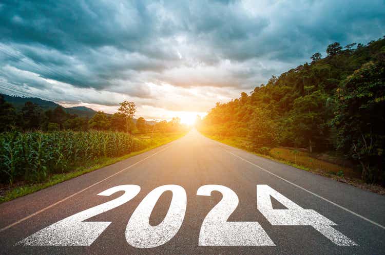 New year 2024 concept. Text 2024 written on the road in the middle of asphalt road with at sunset. Concept of planning, goal, challenge, new year resolution.