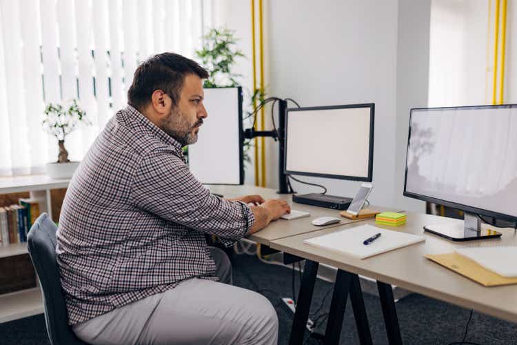 Male software developer working with computers and data systems in office