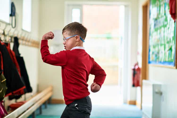 Boy with Down syndrome flexing muscles in school corridor