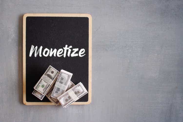 Top view stack of money and text MONETIZE with copy space for text.