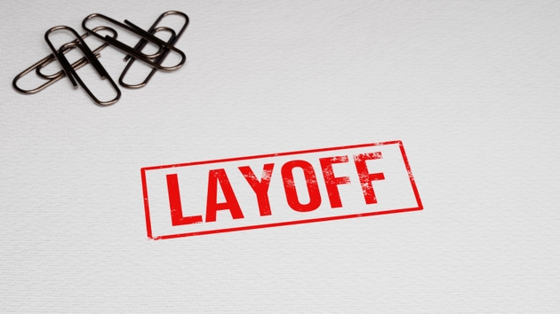 LAYOFF rubber stamp on paper with paper pins in the background. 3D illustration