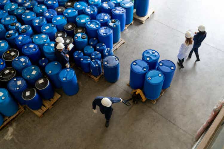 Employees working at a chemical plant moving barrels of substances