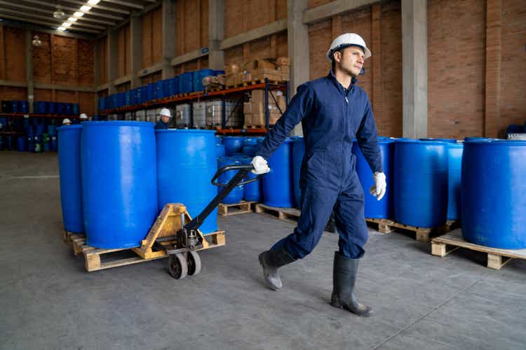 Chemical plant worker moving barrels using a forklift