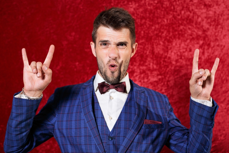 Portrait of cheerful man in suit showing horn sign