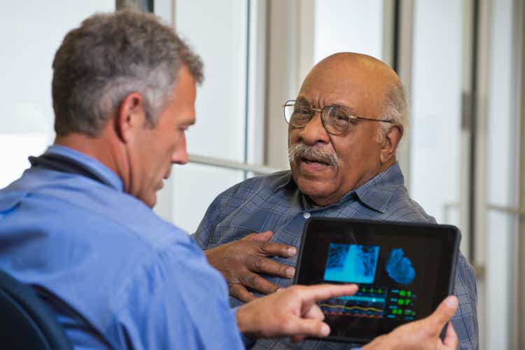 Doctor talking to patient in hospital using digital tablet