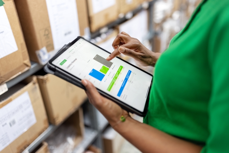 Close-up of warehouse manager using inventory management system on digital tablet
