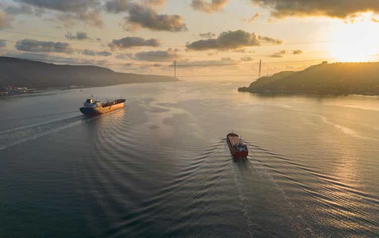 Aerial view tanker ship with liquid bulk cargo and cargo ship in transit at sunrise.