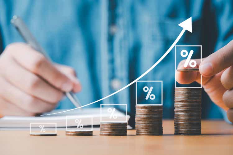 Businessman hand stacking coins with virtual increasing graph and percentage for Business investment profit and deposit dividend saving growth concept.