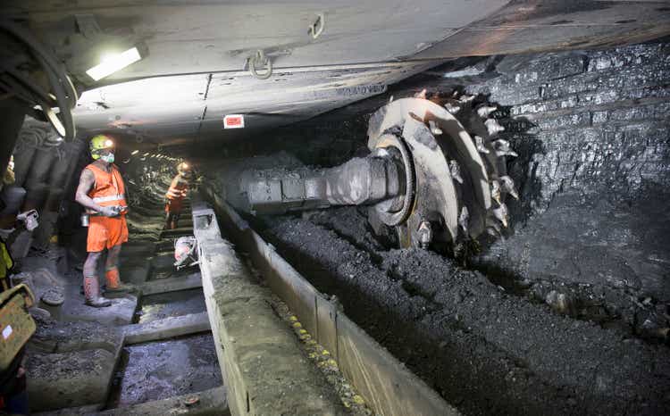 Miners cutting coal at coal seem in deep mine