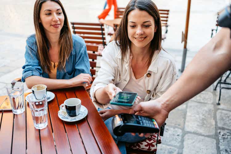 Young Woman Paying Via Contactless Channel By Mobile Banking Application In A Sidewalk Café In Dubrovnik