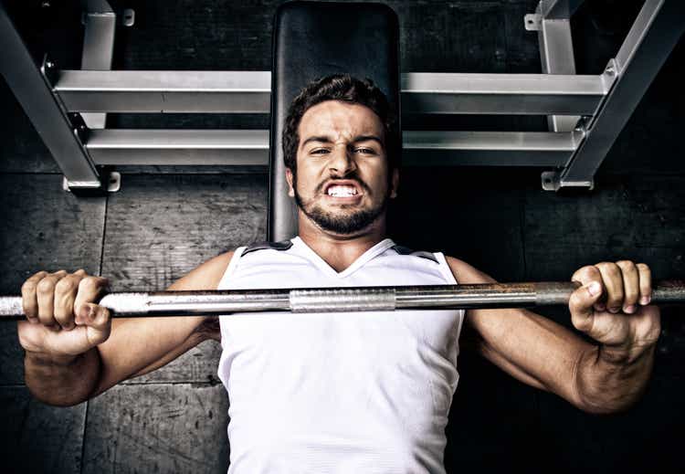 Young man putting effort in on a bench press