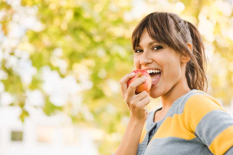 Веселая молодая женщина еда apple