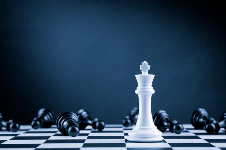 White Chess King among lying down black pawns on chessboard