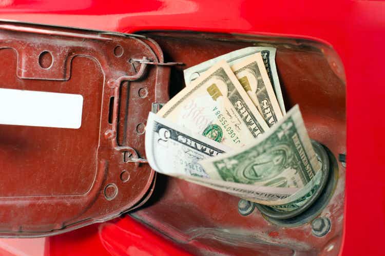 Money in the chute of a gas representing high gas prices