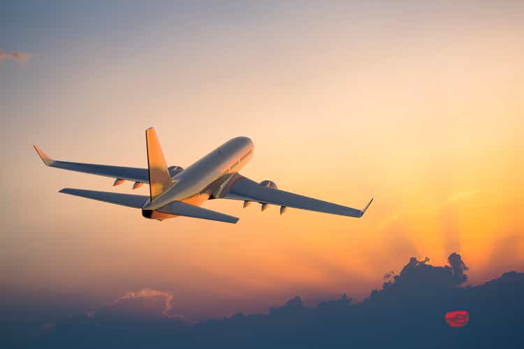 Passenger plane flying above the clouds at sunset