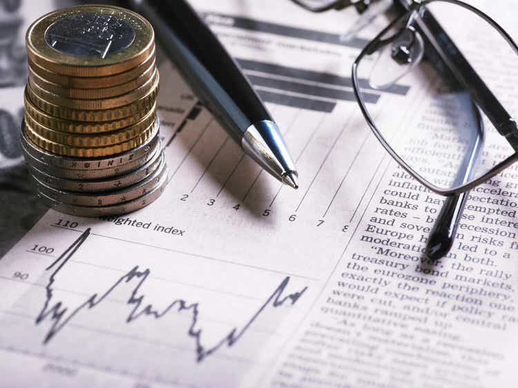 A financial chart with coins, glasses and pen